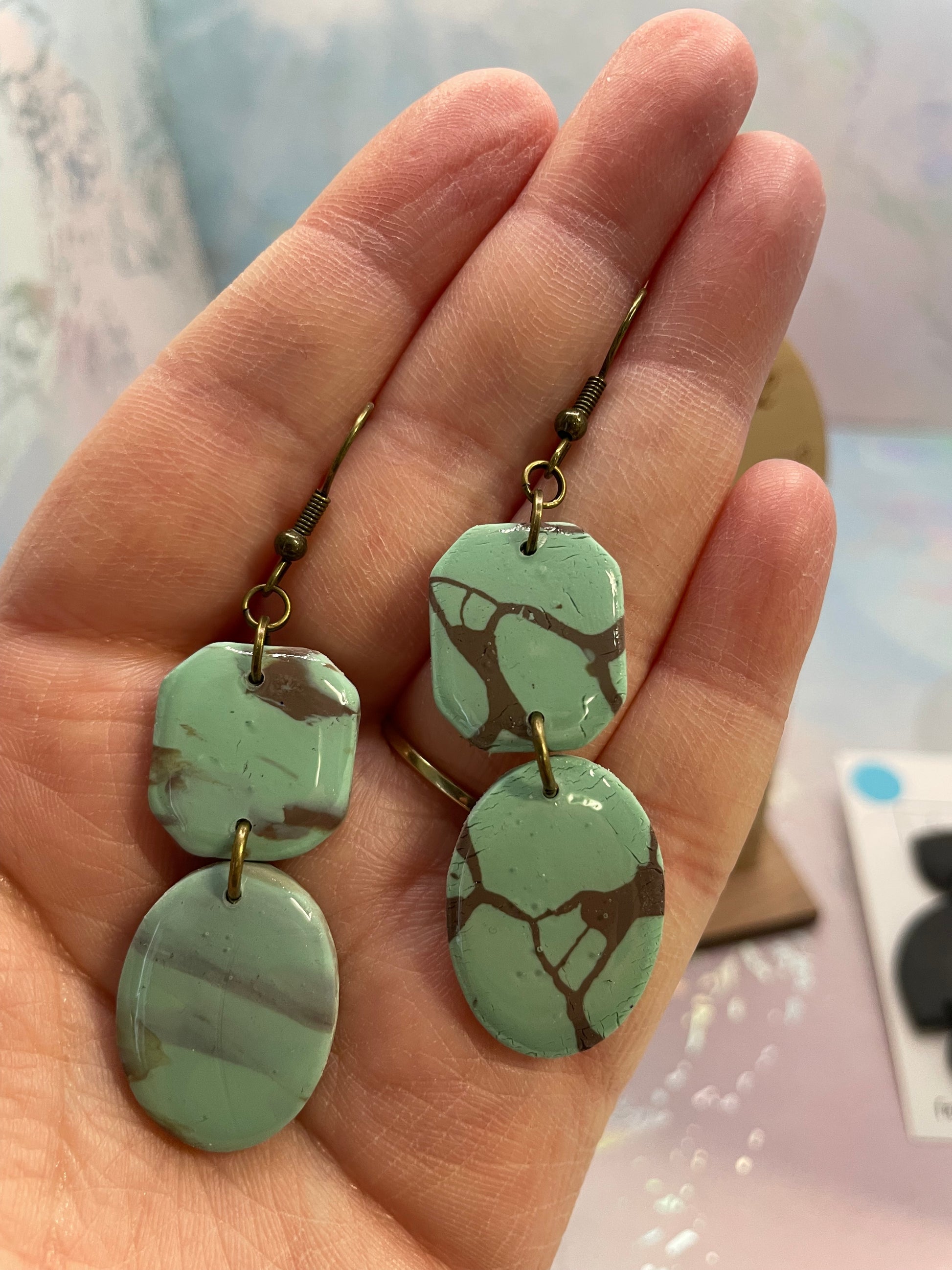 Hand holding a pair of shayna earrings with bronze fishhook