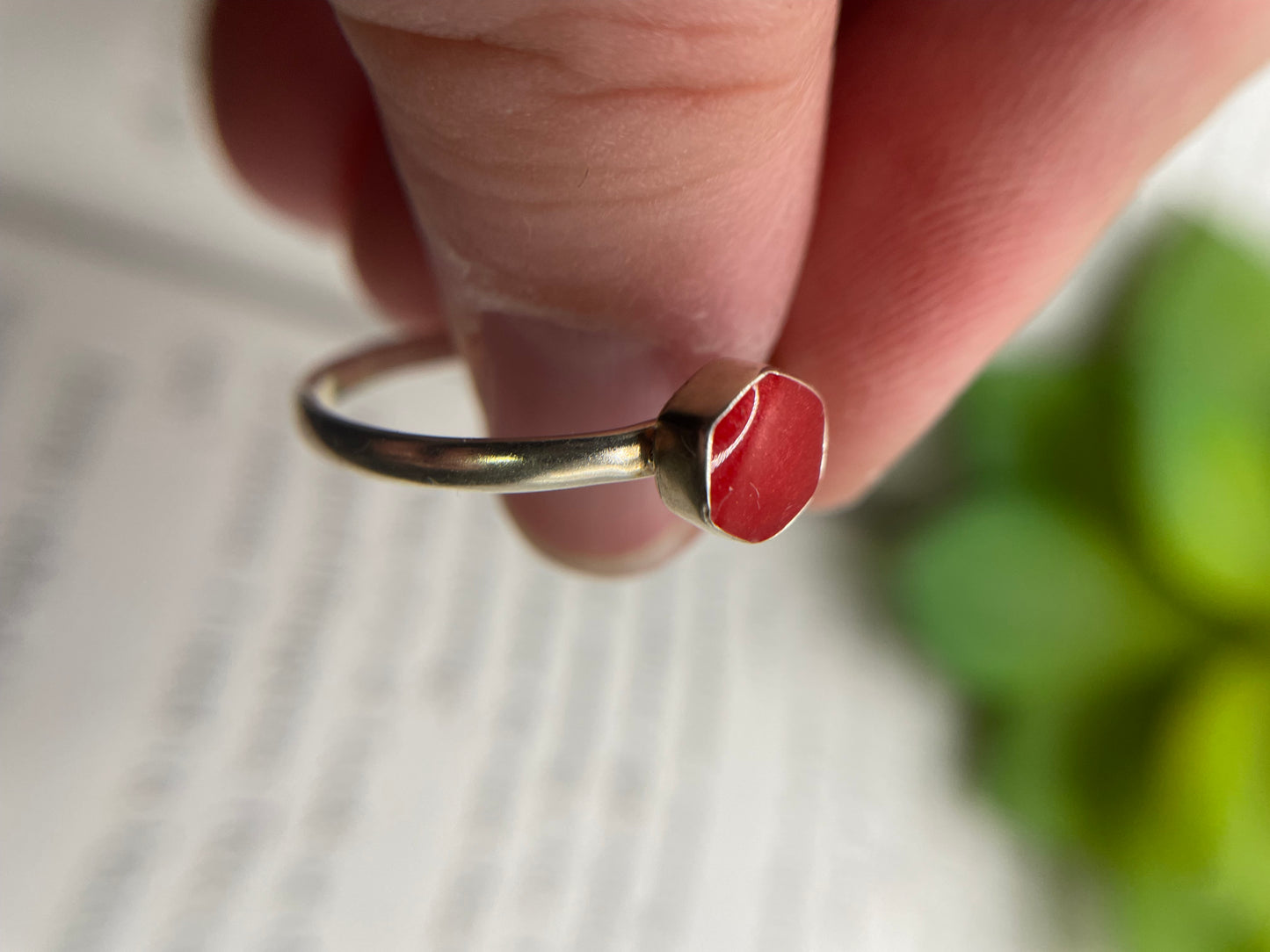 Ring with a red stone on a finger against a blurred background
