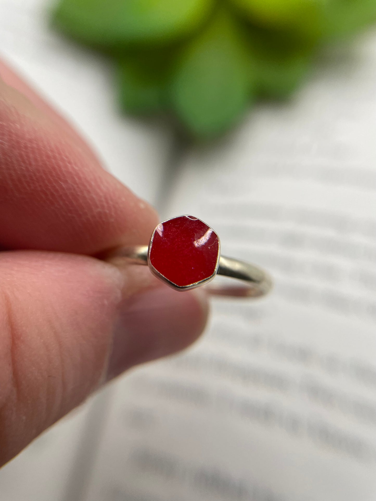 Ring with a red gemstone held by a hand against a blurred background