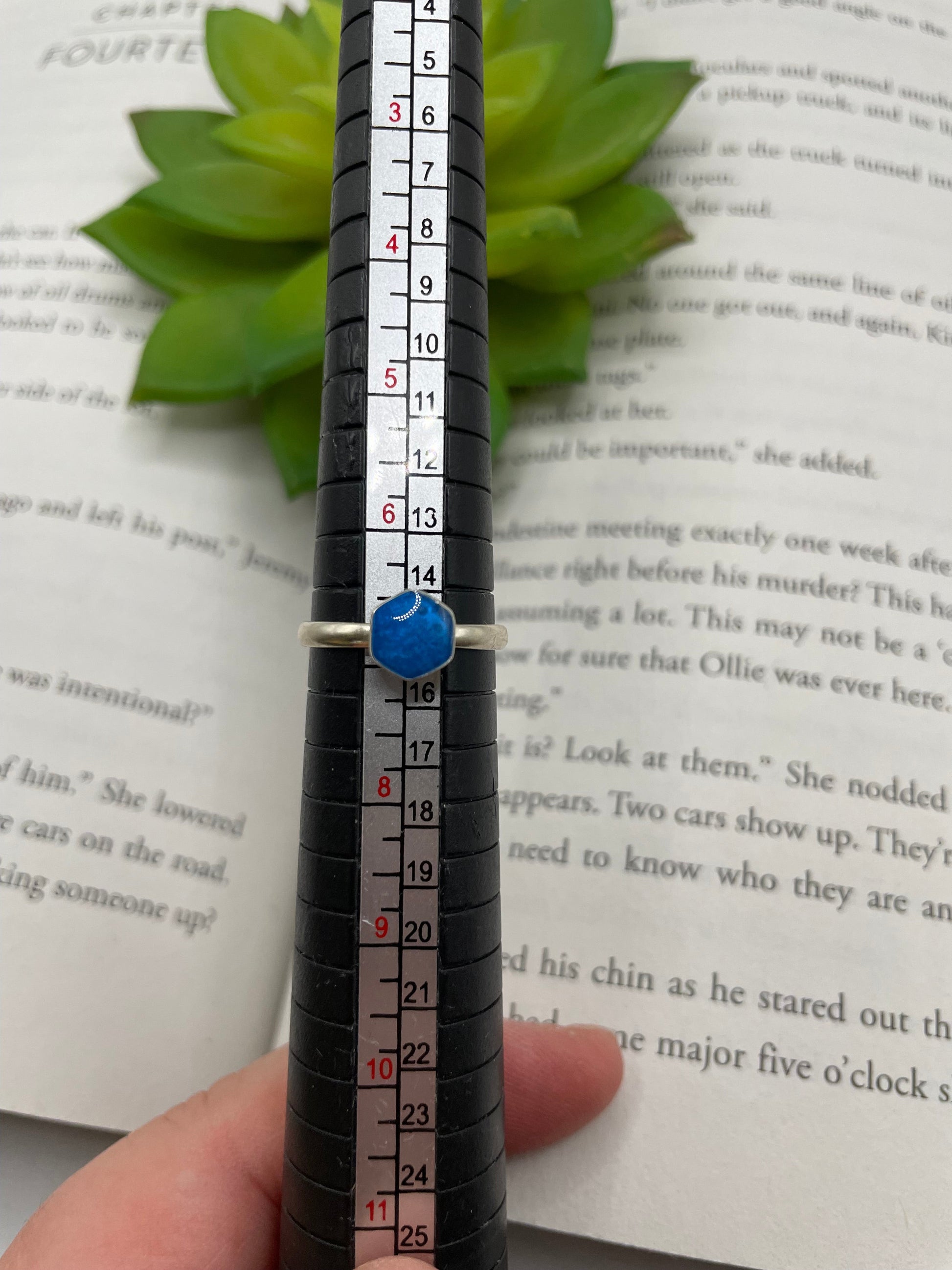 Measurement of a blue stone on a black cylindrical object against a book background