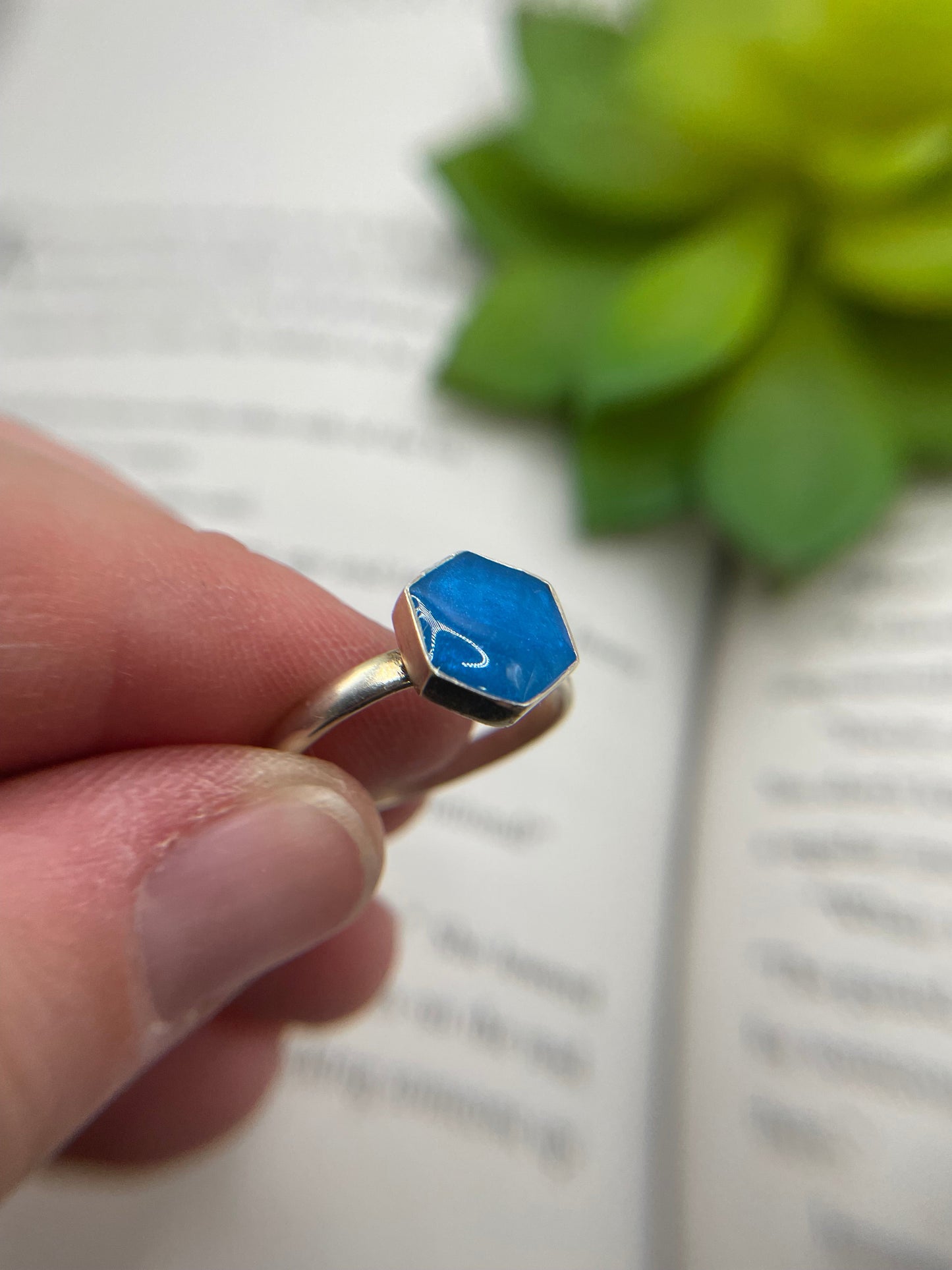 Hand holding a blue geometric ring with a blurred background