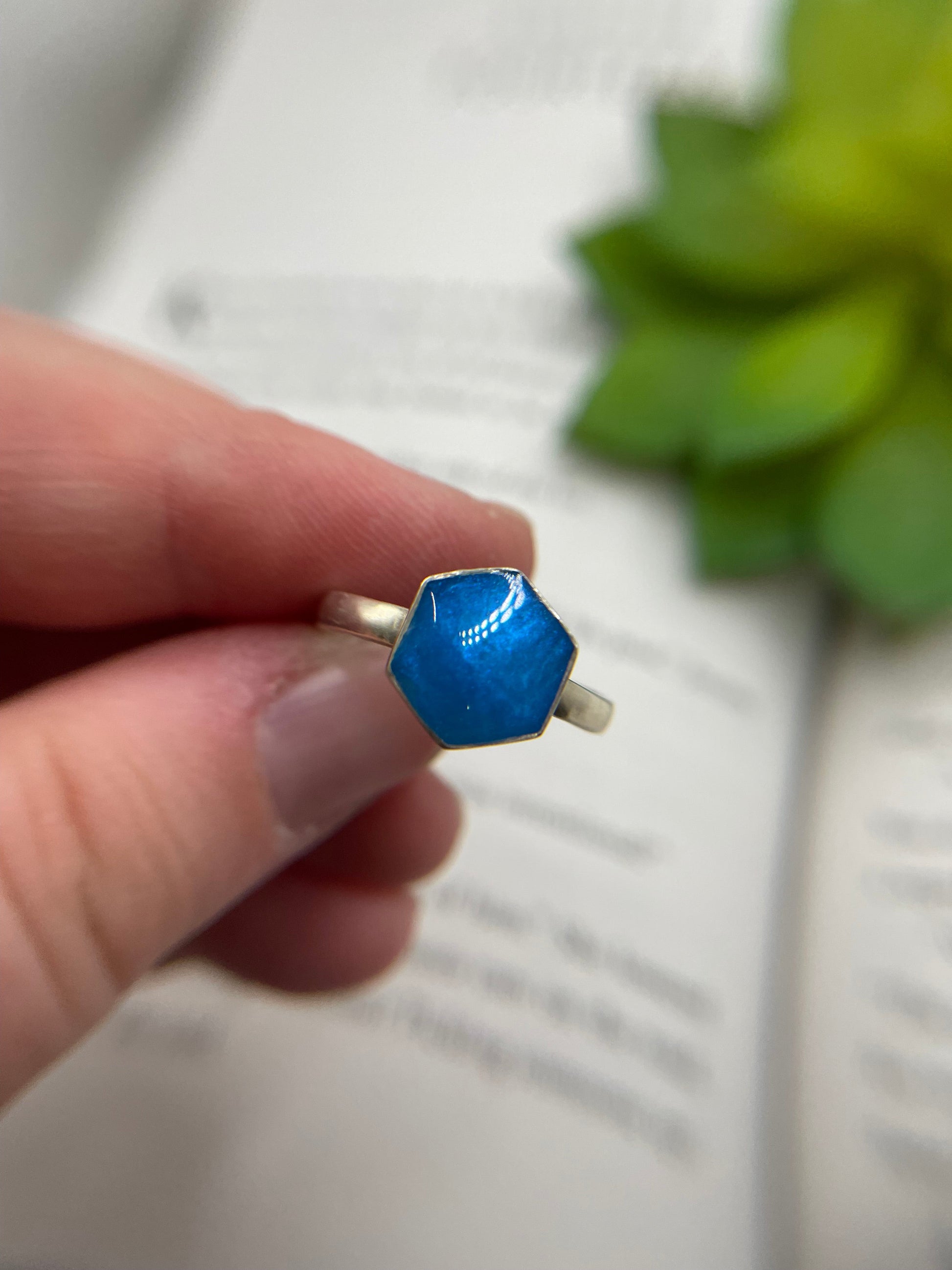 Hand holding a blue ring with a blurred background