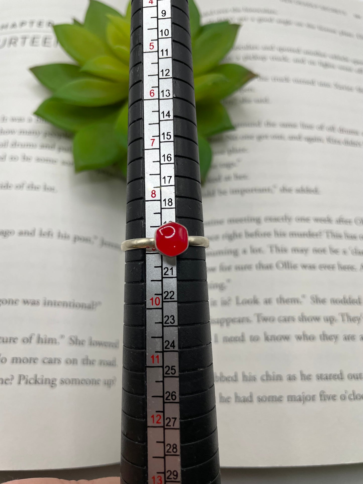 Red ring with white band on a ruler over an open book