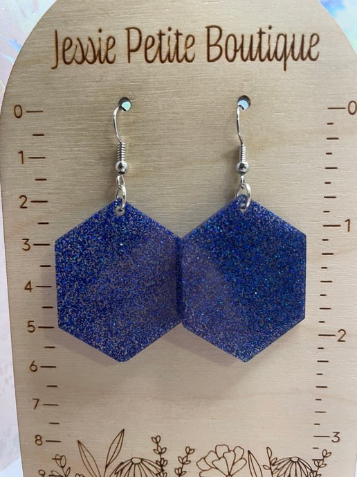 Blue glittery hexagonal earrings on a wooden card with 'Jessie Petite Boutique' branding.