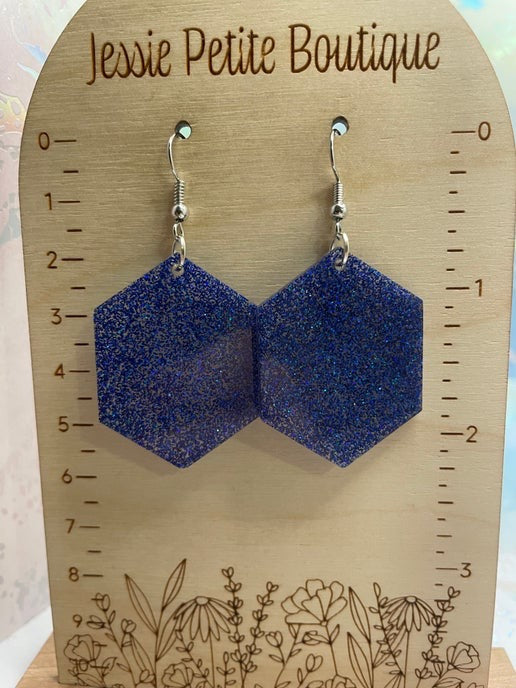 Blue glittery hexagonal earrings on a wooden card with 'Jessie Petite Boutique' branding.
