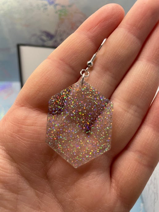 Sparkly earring held in a hand with a blurred background