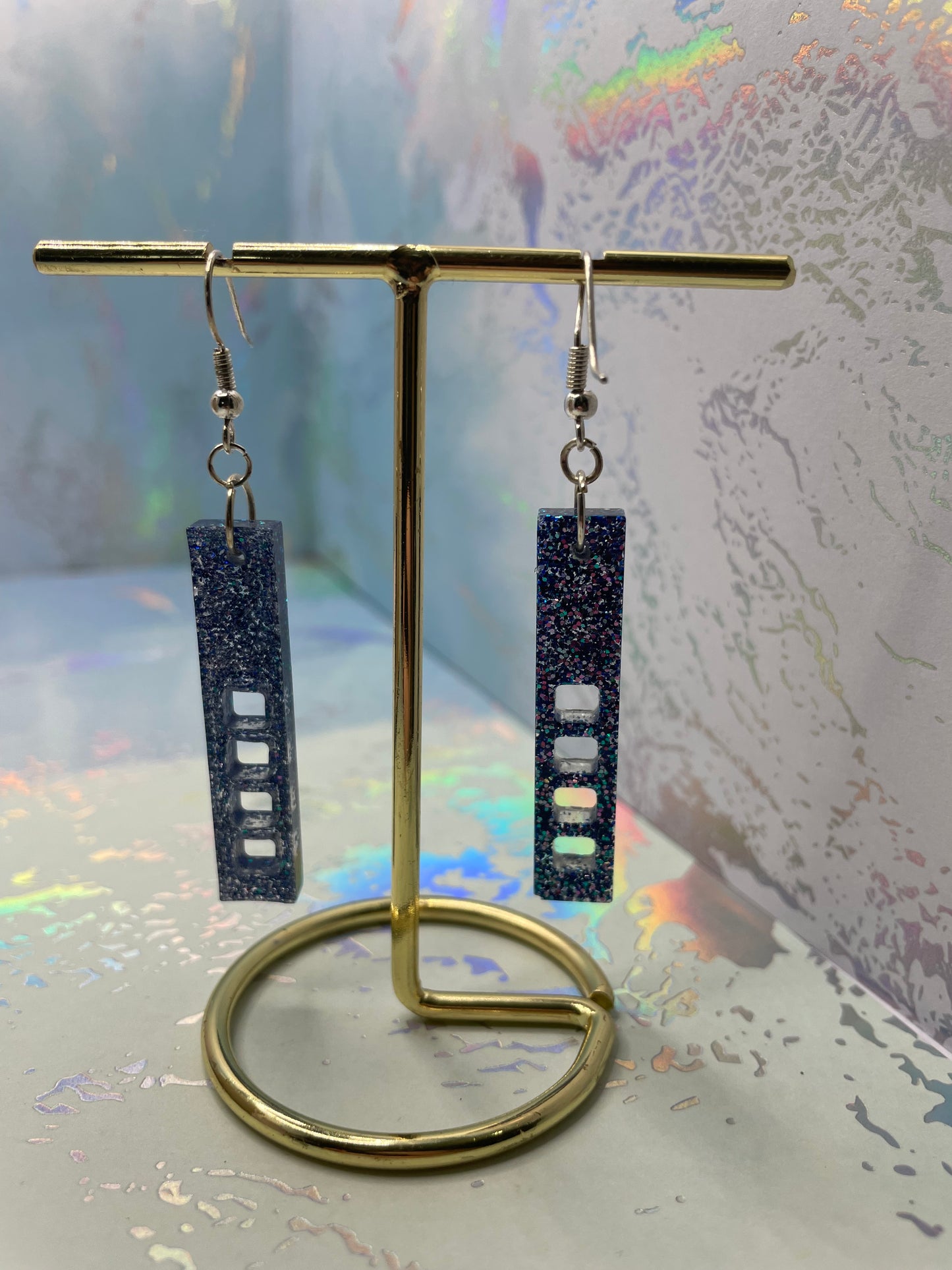Pair of sparkly purple:skyscraper earrings on a reflective surface