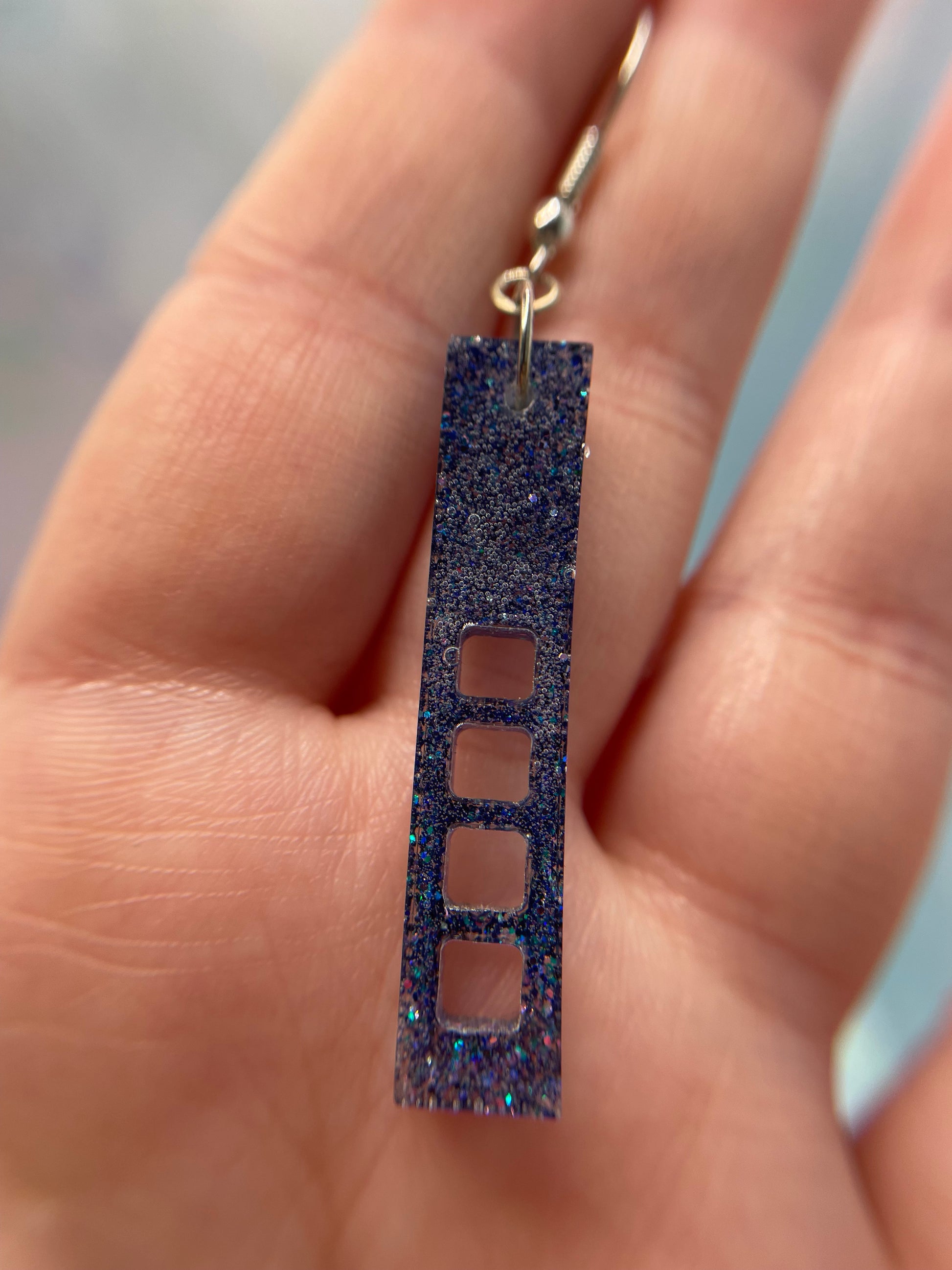 sparkly purple:skyscraper earring held between fingers