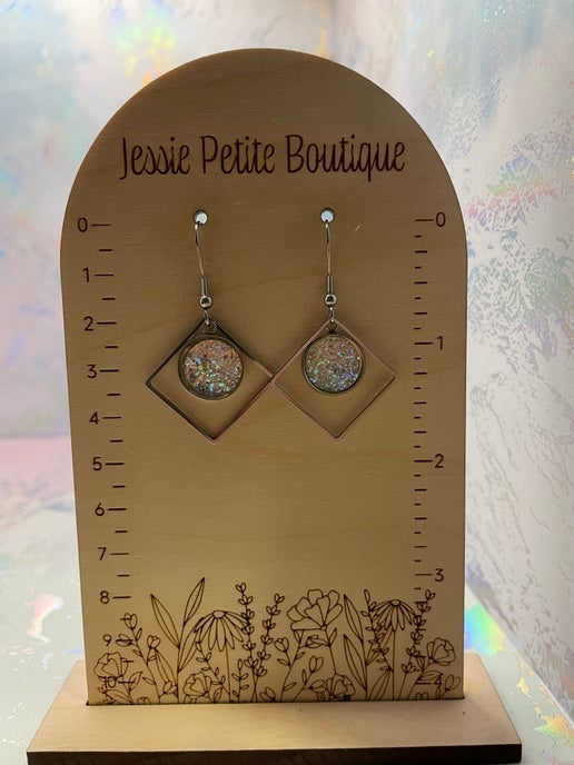 Pair of earrings on a wooden display stand with 'Jessie Petite Boutique' branding.