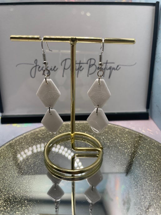 Pair of earrings on a gold stand with a blurred background