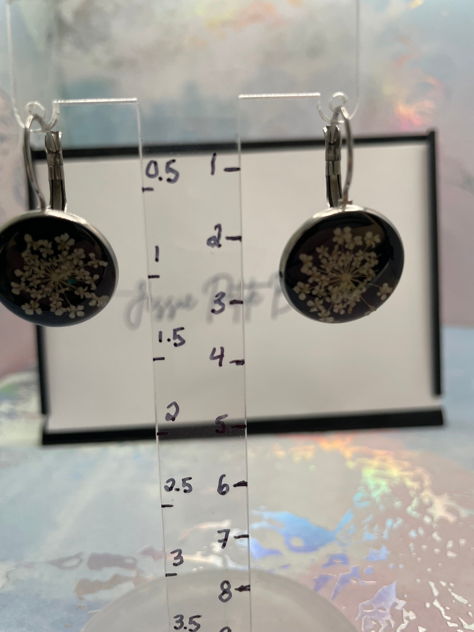 earrings with floral design on a transparent stand against a blurred background