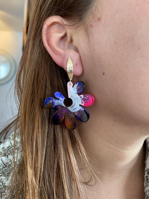 Close-up of a colorful floral earring worn by a person.