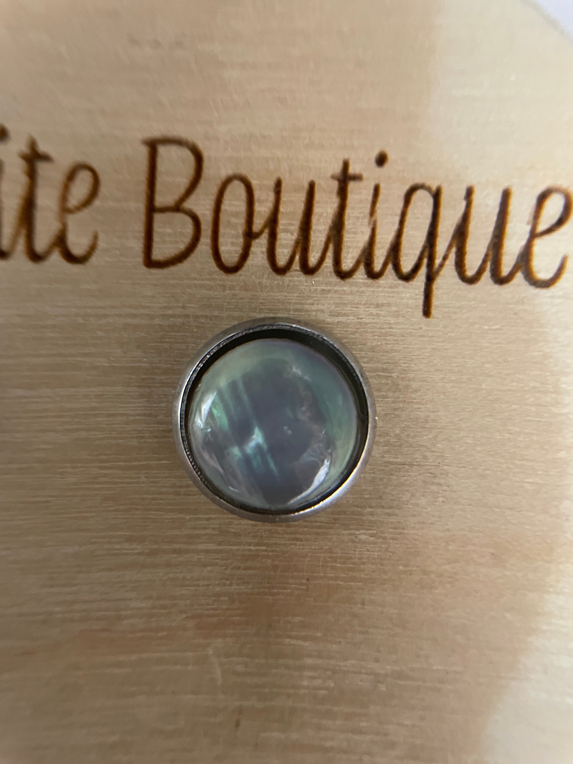 white shell cabochon stud with 'Jessie Petite Boutique' engraving on a wood background
